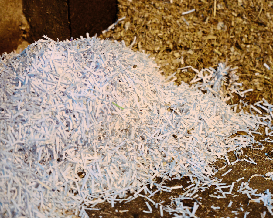 A pile of paper on a stable floor is pictured. This is a type of horse bedding