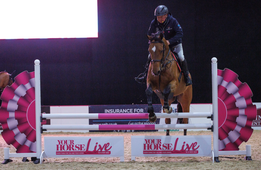 Geoff Billington is pictured jumping a pink and white Your Horse Live fence during his demo at Your Horse Live in 2023 